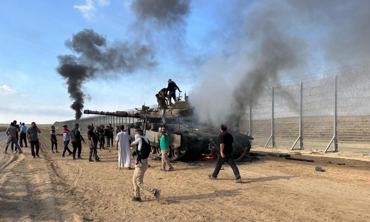 <span>Hamas militants burning an Israeli armoured vehicle in Khan Younis, Gaza, on 7 October 2023.</span><span>Photograph: APAImages/Shutterstock</span>