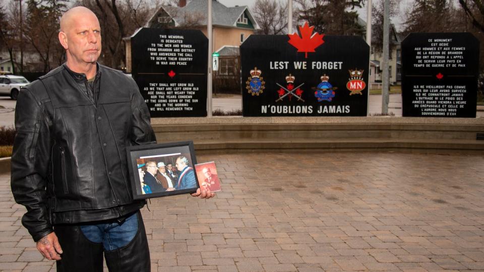 Tim Yakabowich holds a photo of his father at a D-Day anniversary celebration by war memorials in Brandon. 