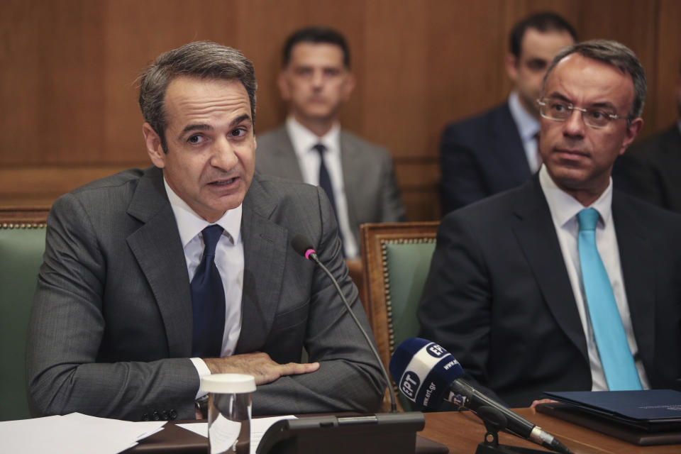 Greek Prime Ministers Kyriakos Mitsotakis, left, speaks next to Finance Minister Christos Staikouras, as new government participate in a first cabinet meeting, in Athens, Wednesday, July 10, 2019. Conservative party leader Kyriakos Mitsotakis won Sunday's election on pledges that included making the country more businesses-friendly, cutting taxes and negotiating an easing of draconian budget conditions agreed as part of the country's rescue program. (AP Photo/Petros Giannakouris)