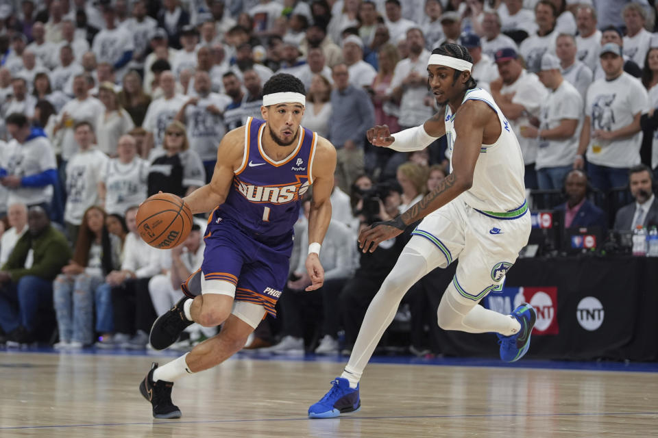 Phoenix Suns guard Devin Booker (1) drives against Minnesota Timberwolves forward Jaden McDaniels during the first half of Game 2 of an NBA basketball first-round playoff series Tuesday, April 23, 2024, in Minneapolis. (AP Photo/Abbie Parr)