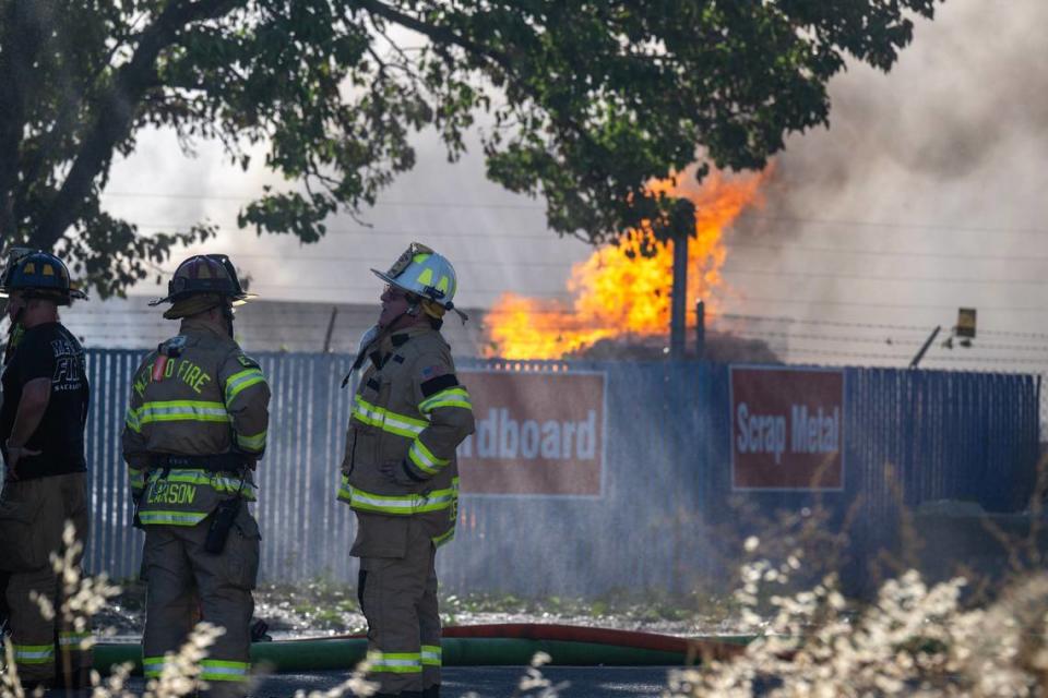 Firefighters wait as water is sprayed on a fire from ladder trucks at Green Evolution Recycling center at 24th Avenue and Florin Perkins Road in south Sacramento on Thursday, July 25, 2024.