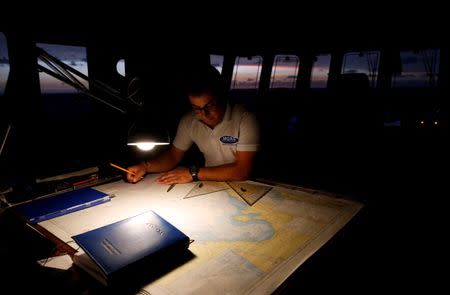 A crew member on the Migrant Offshore Aid Station (MOAS) ship Topaz Responder looks at navigation charts as the ship stands by for migrants in distress in international waters off the coast of Libya, June 21, 2016. REUTERS/Darrin Zammit Lupi