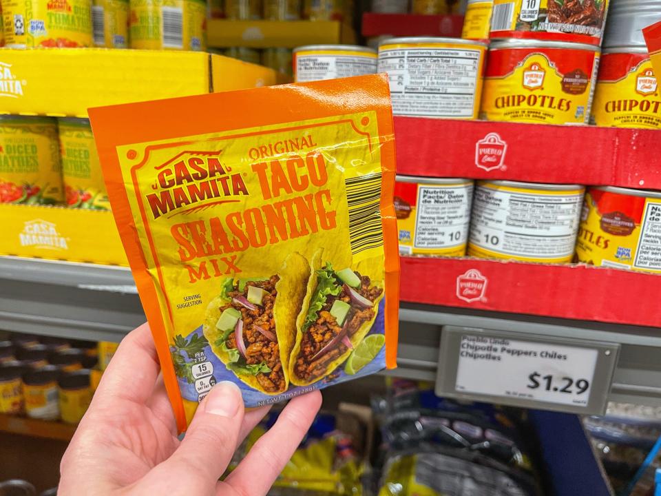 The writer holds a yellow and red packet of taco seasoning