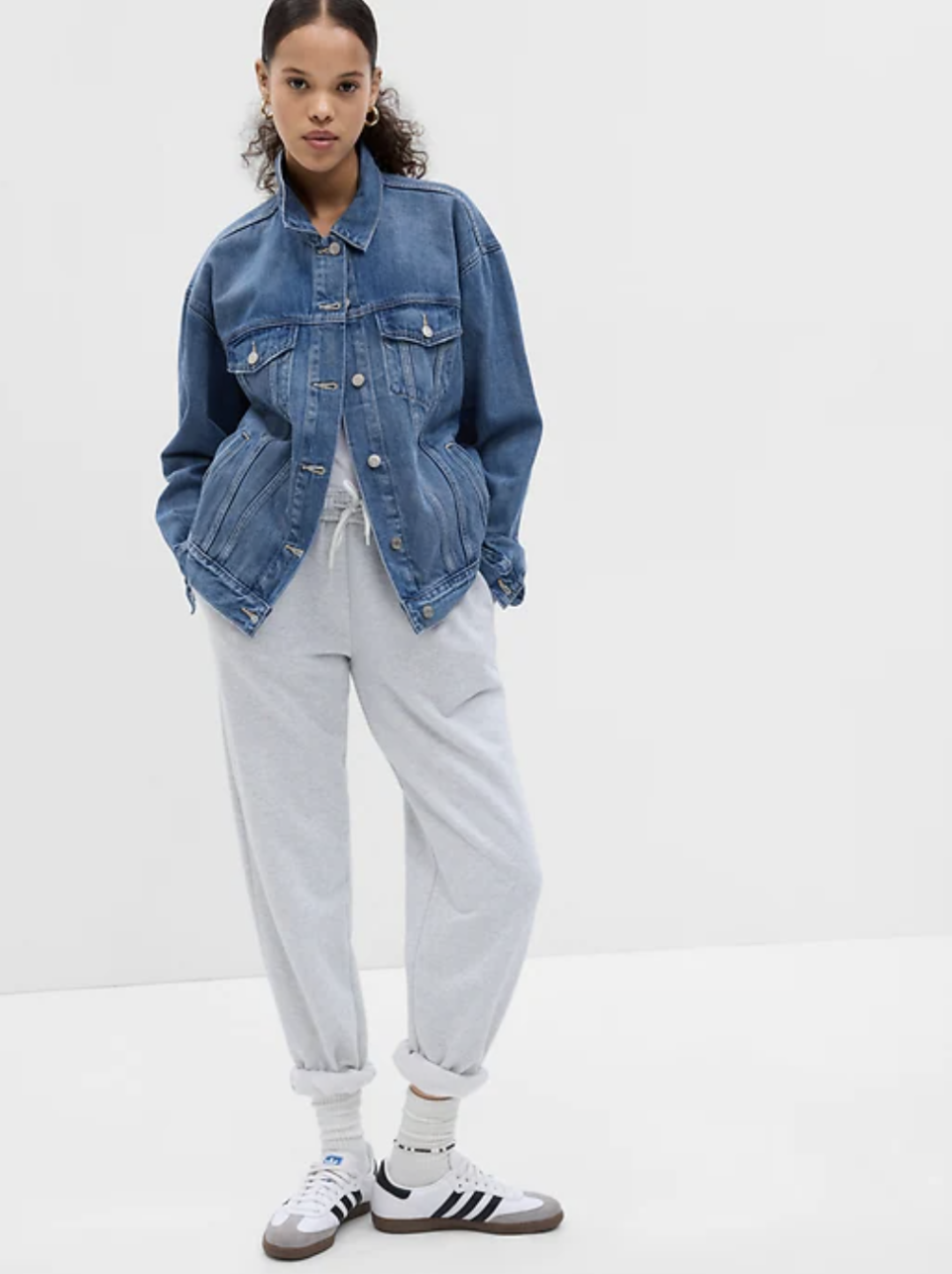 model wearing grey sweatpants and blue Oversized Icon Denim Jacket (photo via Gap)