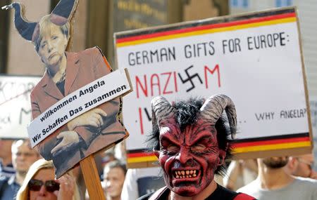 A protester holds a banner during a demonstration against German Chancellor Angela Merkel in Prague, Czech Republic, August 25, 2016. The sign (L) reads, "Welcome Angela, Together We Can Make It". REUTERS/David W Cerny