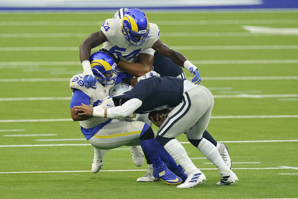 Dallas Cowboys quarterback Dak Prescott, right, is tackled by Los Angeles Rams defensive end Aaron Donald, left and outside linebacker Leonard Floyd (54) top during the first half of an NFL football game Sunday, Sept. 13, 2020, in Inglewood, Calif. (AP Photo/Ashley Landis )