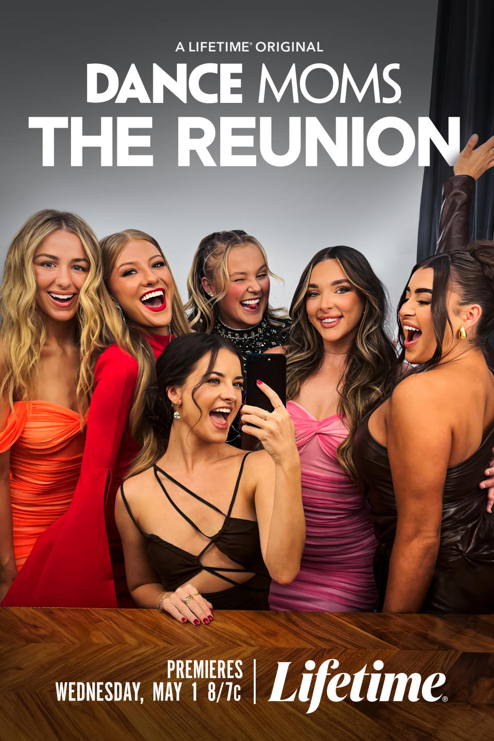 Reunion poster of 'Dance Moms' cast with six women smiling, posing for a selfie, dressed in elegant evening wear
