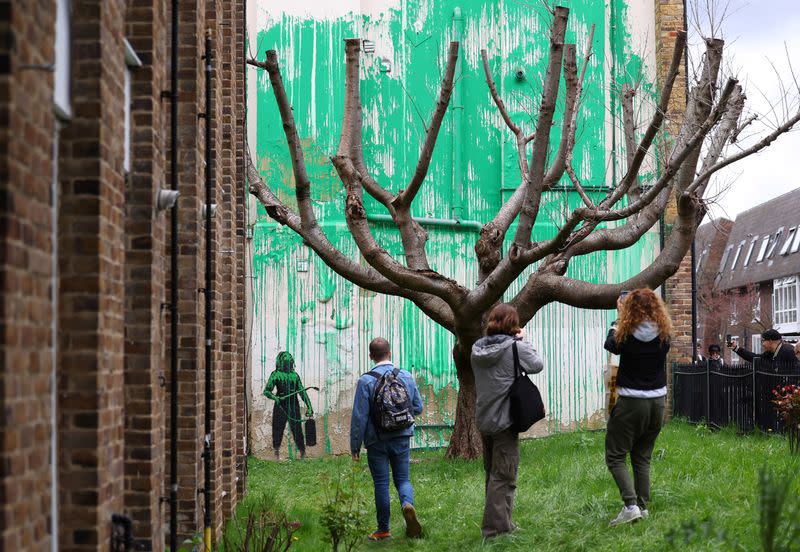 Un grupo de personas observa un nuevo mural atribuido al artista británico Banksy en una pared del norte de Londres, Reino Unido