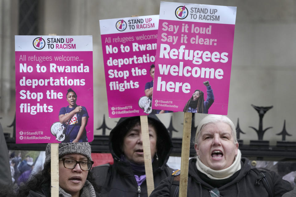 Stand Up To Racism campaigners hold banners outside the High Court in London, Monday, Dec. 19, 2022. Judges at Britain’s High Court say the U.K. government’s controversial plan to send asylum-seekers on a one-way trip to Rwanda is legal. But two judges also ruled that the government failed to consider the circumstances of the individuals it tried to deport. (AP Photo/Kirsty Wigglesworth)