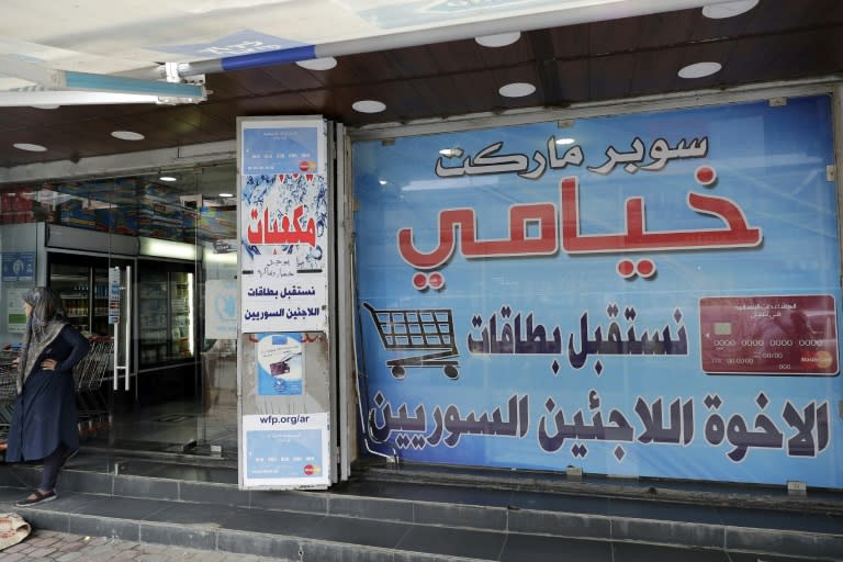 A poster reading "we accept the cards of our Syrian refugee brothers and sisters" covers the window of Khiami grocery store in Beirut on June 14, 2017