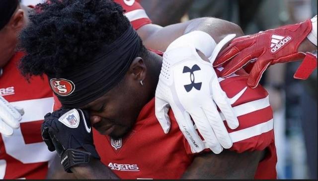 Grieving Marquise Goodwin kneels before playing for his San Francisco 49ers against the New York Giants Nov. 12, 2017. It was hours after he and his wife lost their first child to a miscarriage.