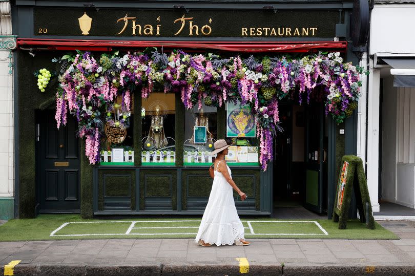 A woman walks past Thai Tho restaurant in Wimbledon Village which is decorated for the tennis tournament