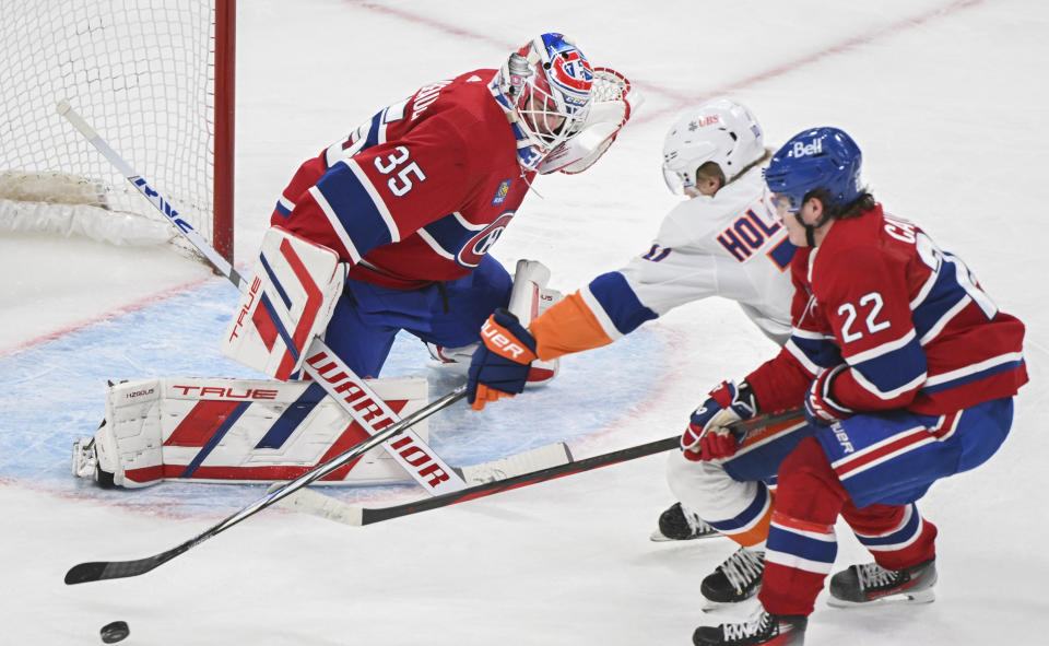 New York Islanders' Simon Holmstrom (10) skates in on Montreal Canadiens goaltender Sam Montembeault as Canadiens' Cole Caufield (22) defends during the second period of an NHL hockey match in Montreal, Saturday, Dec. 16, 2023. (Graham Hughes/The Canadian Press via AP)