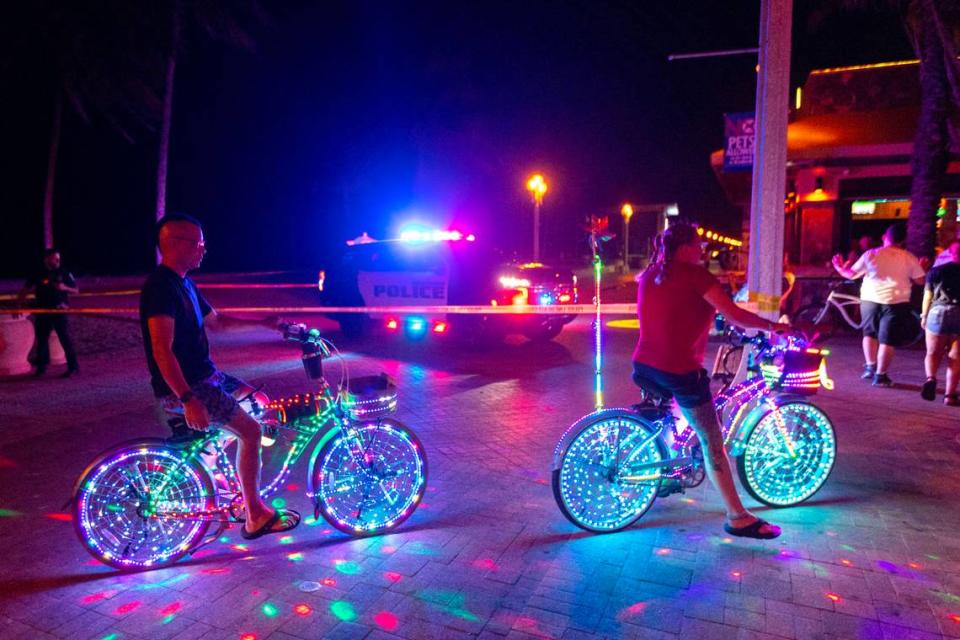 Pedestrians and bicyclist move around a Hollywood Police Car as it sits parked on the 1214 block of North Broadwalk near Nick’s Bar and Grill after police responded to reports of multiple people shot during Memorial Day weekend at Hollywood, Florida, on Monday, May 29, 2023.