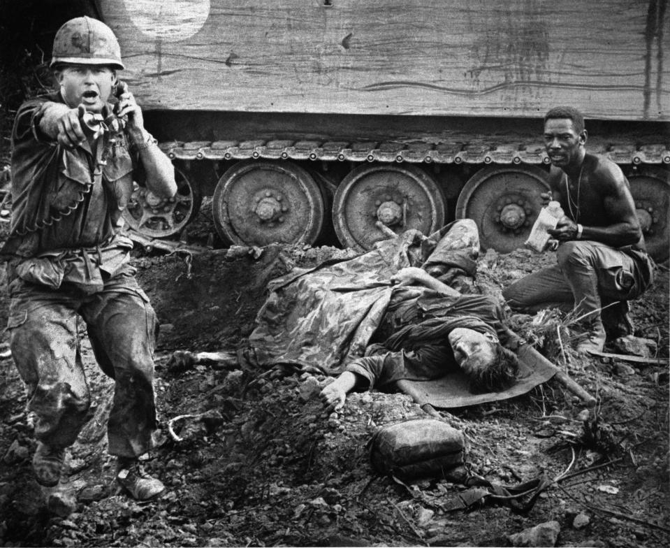 During an ambush near Saigon by Viet Cong guerrillas, an officer shouts orders as a wounded American soldier awaits evacuation near Saigon during the Vietnam War, 1969. The soldier is attended by a medic as they seek cover beside an armored troop carrier. (AP Photo/Oliver Noonan)