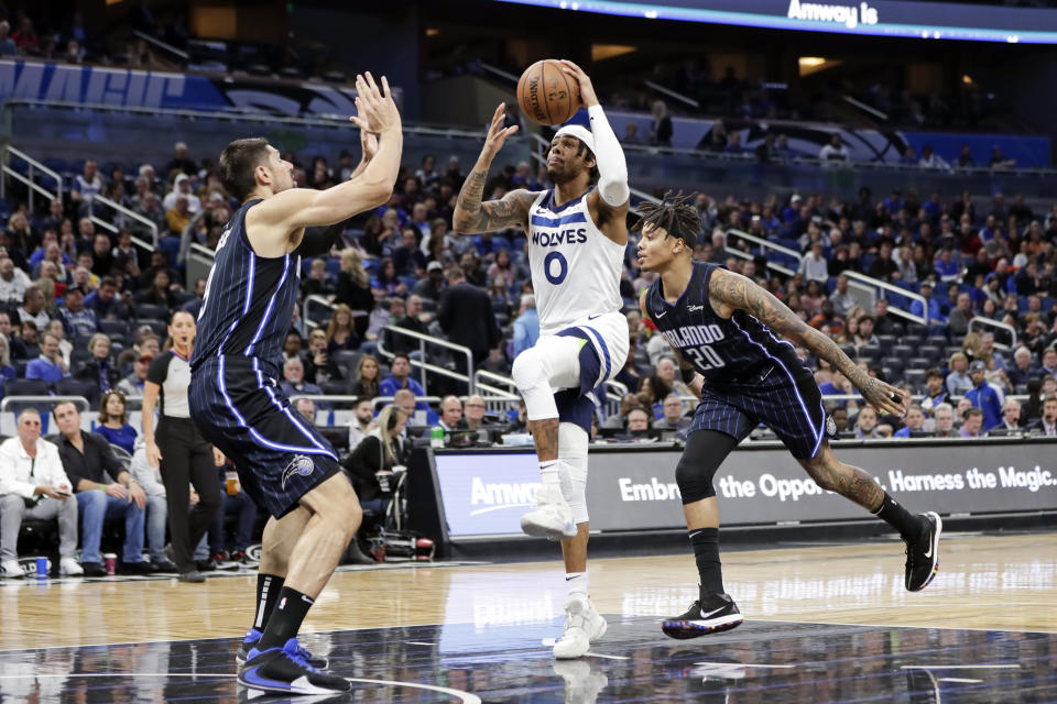 Minnesota Timberwolves guard D'Angelo Russell (0) goes up for a shot between Orlando Magic center Nikola Vucevic, left, and guard Markelle Fultz (20) during the first half of an NBA basketball game Friday, Feb. 28, 2020, in Orlando, Fla. (AP Photo/John Raoux)