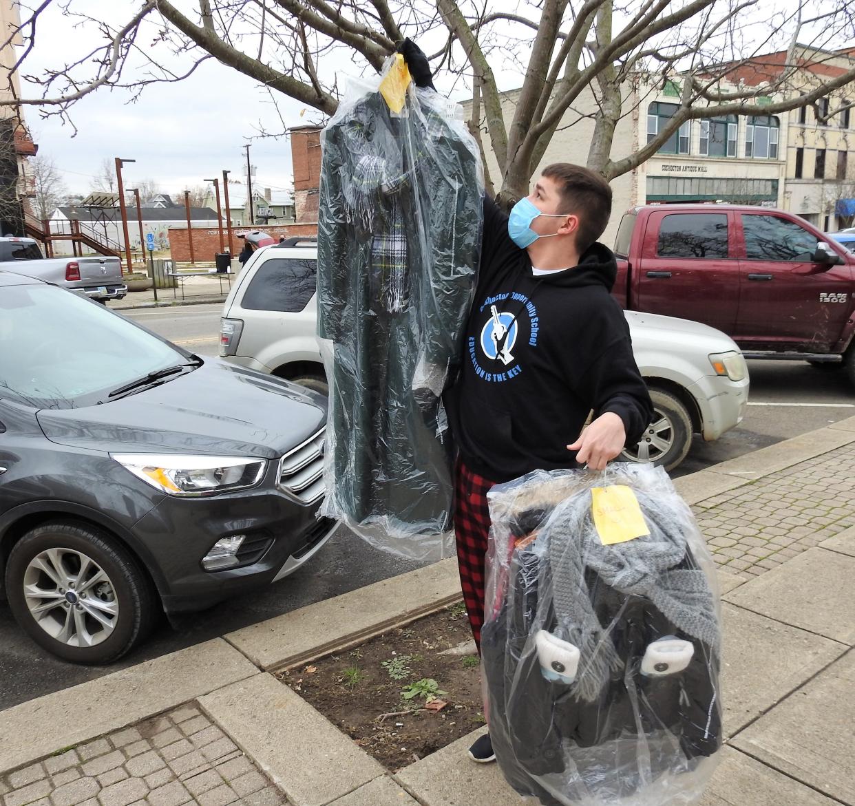 Bailee Cass, a student at the Coshocton Opportunity School, hangs coats on Main Street for the needy and homeless, as part of a winter clothing drive in 2020. The project is returning this year with clothing to be hung on trees on Dec. 13.