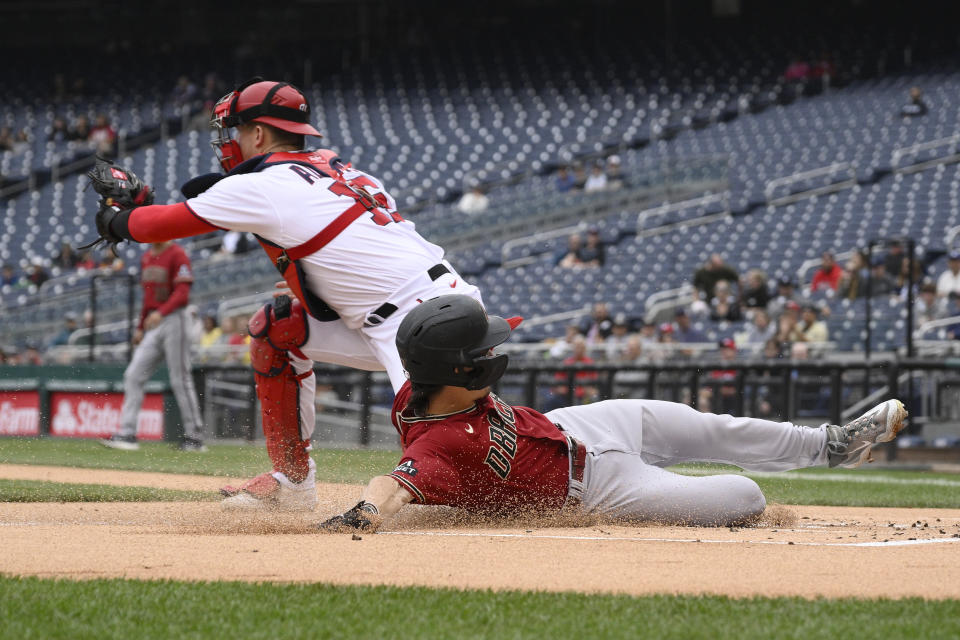 Arizona Diamondbacks' Corbin Carroll slides home to score on a single by Christian Walker as Washington Nationals catcher Riley Adams waits for the throw during the first inning of a baseball game, Thursday, June 22, 2023, in Washington. (AP Photo/Nick Wass)