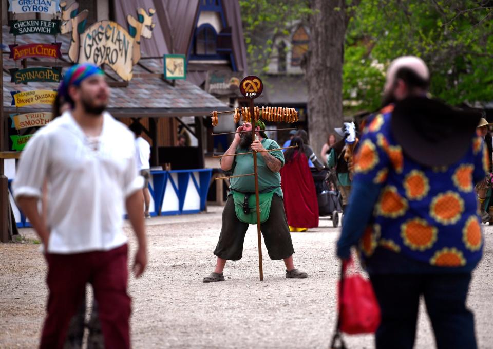 A barker sells oversized pretzels as patrons walk by at the fair.