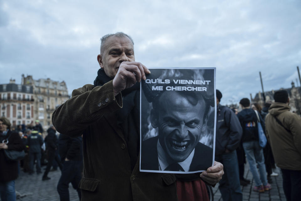 A protester holds a placard with the face of Macron reading 'They have to come for me' during a protest in Paris, Saturday, March 18, 2023. A spattering of protests were planned to continue in France over the weekend against President Macron's controversial pension reform, as garbage continued to reek in the streets of Paris and beyond owing to continuing action by refuse collectors. (AP Photo/Lewis Joly)