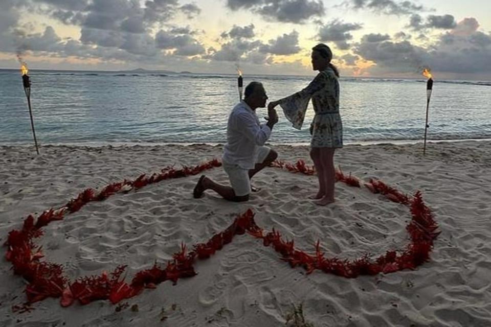 Paty standing as her fiance gets down on one knee (Instagram)