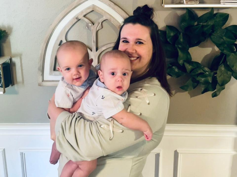 Mom Cara Winhold poses in her home while carrying her baby boys who were conceived a week apart due to a medical phenomenon called superfetation.