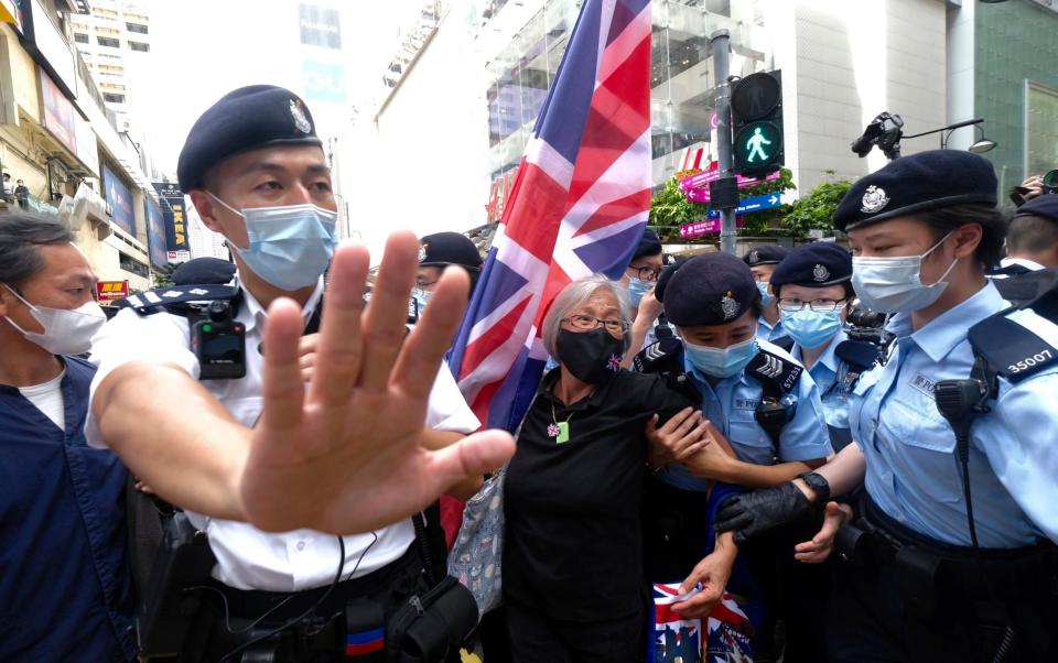 A protester holding a British flag is arrested by police officers on July 2021, the 24th anniversary of Hong Kong's handover from the UK to China - AP