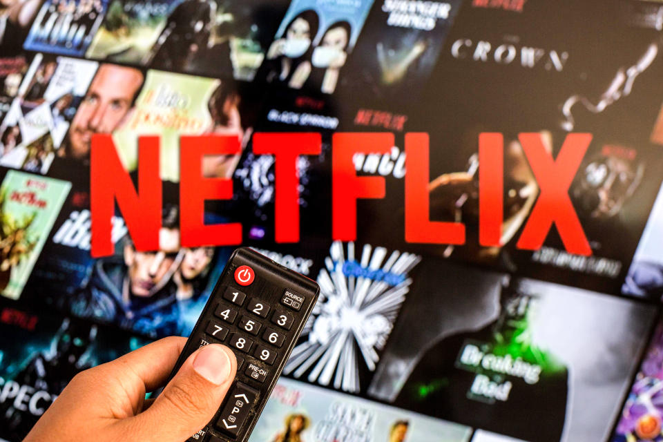 SPAIN - 2021/07/13: In this photo illustration a close-up of a hand holding a TV remote control seen displayed in front of the Netflix logo. (Photo Illustration by Thiago Prudencio/SOPA Images/LightRocket via Getty Images)