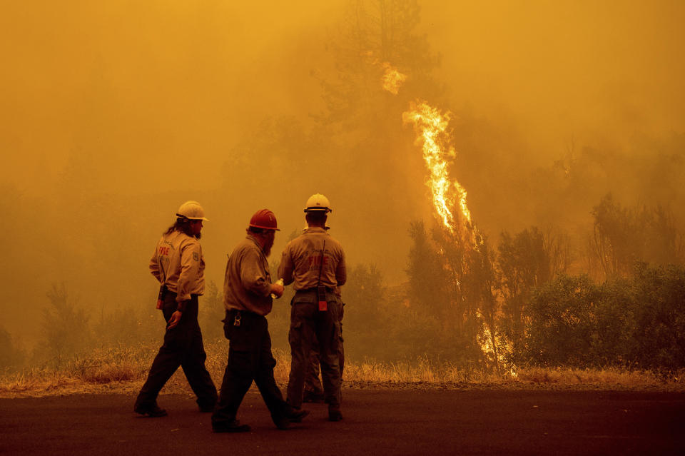 Flames from the McKinney Fire burn beyond firefighters in Klamath National Forest, Calif., on Sunday, July 31, 2022. (AP Photo/Noah Berger)