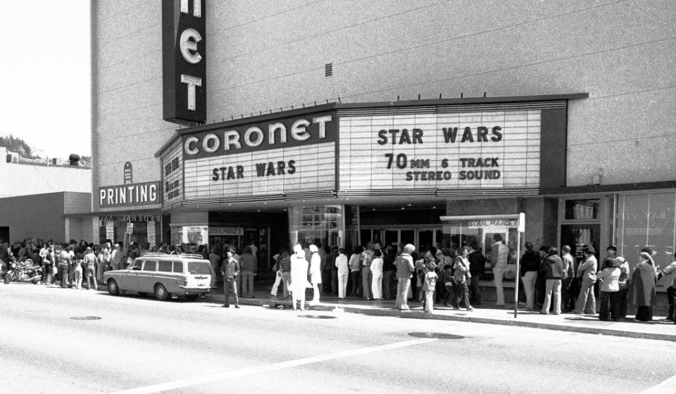 Black-and-white image of a crowd lined up outside the Coronet theater in San Francisco, California in 1977 to see "Star Wars" as shown on the marquee