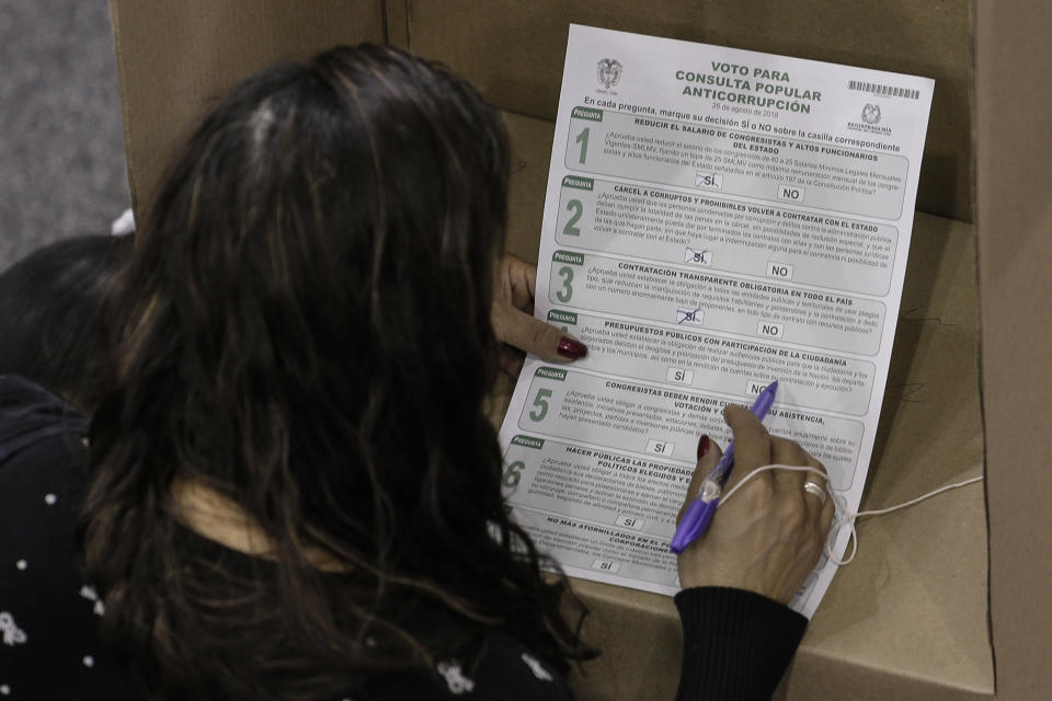 An electoral official count ballots after the closing of a nationwide referendum seeking to curb corruption in Bogota, Colombia, Sunday, Aug. 26, 2018. Voters were asked to approve seven proposals that referendum supporters hope will bring about tougher anti-corruption legislation, but the referendum will only be valid if a third of all voters take part. (AP Photo/Ivan Valencia)