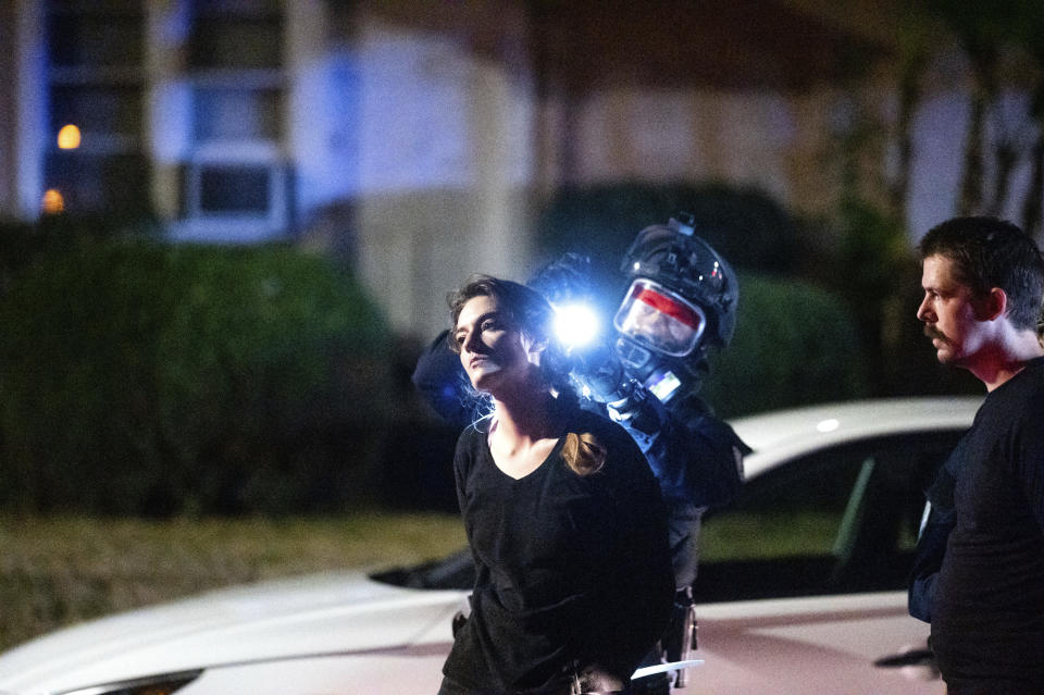 A police officer searches a woman during the 100th consecutive day of demonstrations in Portland, Ore., on Saturday, Sept. 5, 2020. The demonstrations, which began over the killing of George Floyd, have led to two deaths and frequent clashes between protesters and law enforcement. (AP Photo/Noah Berger)