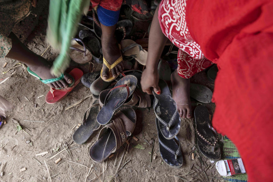 In this July 26, 2019 photo, Ethiopian migrant girls put on their slippers to go and eat outside their lockup known in Arabic as a "hosh," in Ras al-Ara, Lahj, Yemen. Some lockups hold as many as 50 women at a time. The women will stay here for several days until their transportation is ready. (AP Photo/Nariman El-Mofty)