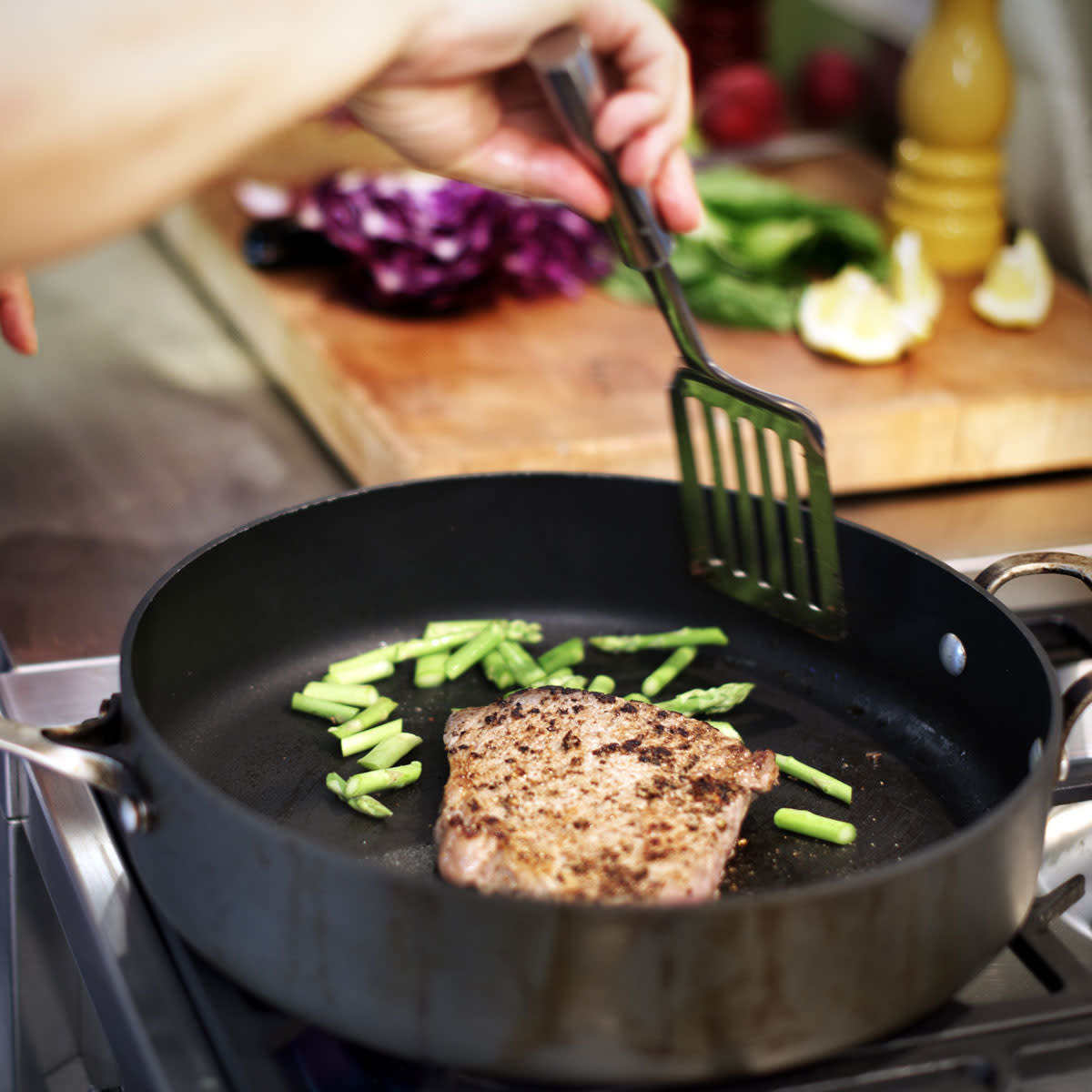 Woman cooking meat and vegetables in a pan