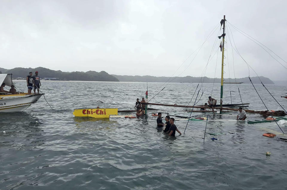 In this photo provided by the Philippine Red Cross, rescuers stand beside the remains of the M/B Chichi ferry boat after it capsized due to bad weather in the waters between Guimaras and Iloilo provinces, central Philippines on Saturday Aug. 3, 2019. Several people died and 31 others were rescued when three ferry boats separately capsized in bad weather Saturday between two central Philippine island provinces, the coast guard said. (Philippine Red Cross via AP)