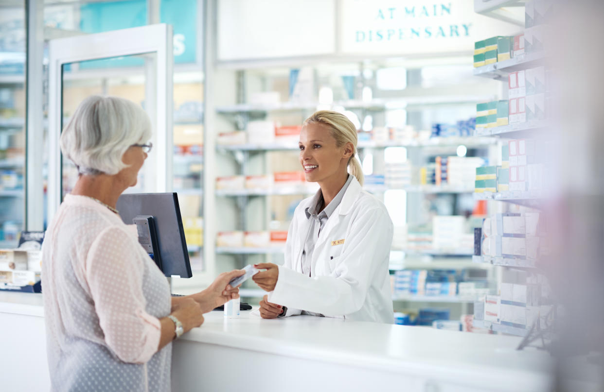 Shot of a young pharmacist helping an elderly customer