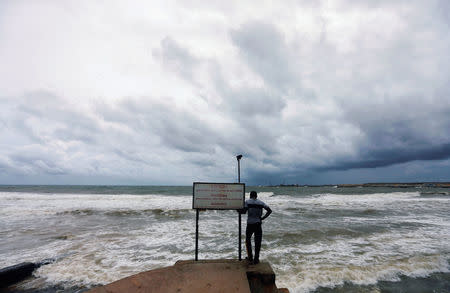 A man looks at the rough sea as rainy clouds gather above during the monsoon period in Colombo, Sri Lanka May 21, 2018. REUTERS/Dinuka Liyanawatte