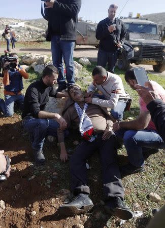 Palestinian minister Ziad Abu Ein (C) falls after being hit by Israeli soldiers during a protest near the West Bank city of Ramallah December 10, 2014. REUTERS/Mohamad Torokman