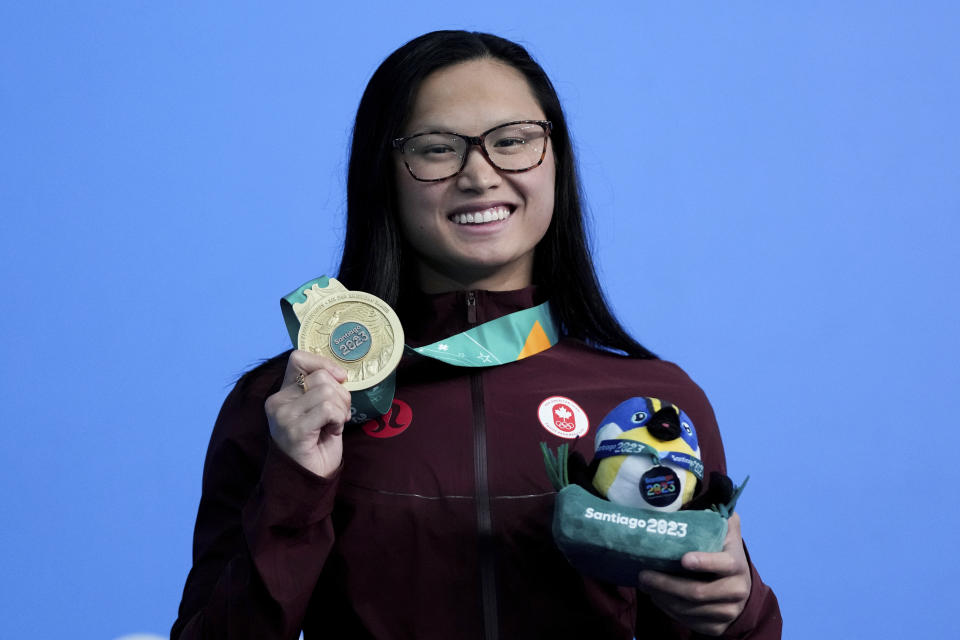 La canadiense Maggie McNeil posa con su medalla de oro tras ganar los 100 metros mariposa en la natación de los Juegos Panamericanos en Santiago, Chile, el domingo 22 de octubre de 2023. (AP Foto/Silvia Izquierdo)