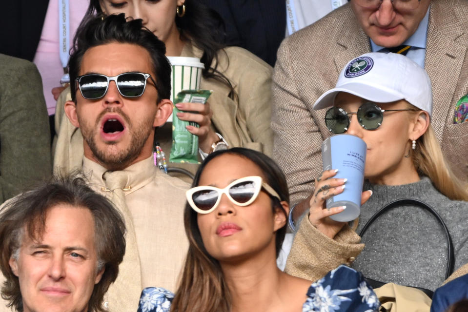 Jonathan with his mouth open and Ariana with a beverage cup to her mouth