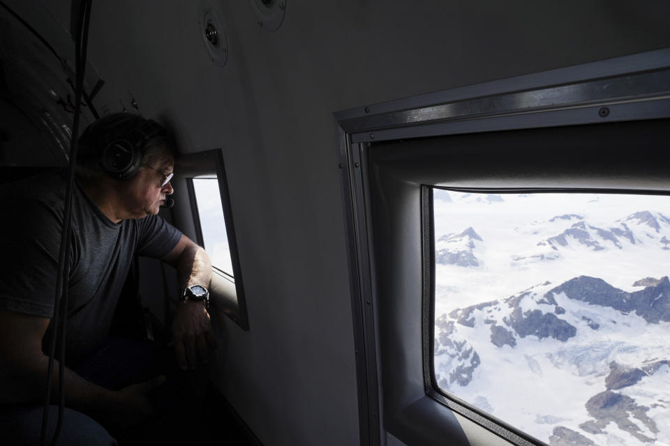 In this photo taken on Wednesday, Aug. 14, 2019, NASA project manager Ian McCubbin looks out of the window of a plane as they fly on a mission to track melting ice in eastern Greenland. Greenland has been melting faster in the last decade and this summer, it has seen two of the biggest melts on record since 2012. (AP Photo/Mstyslav Chernov)