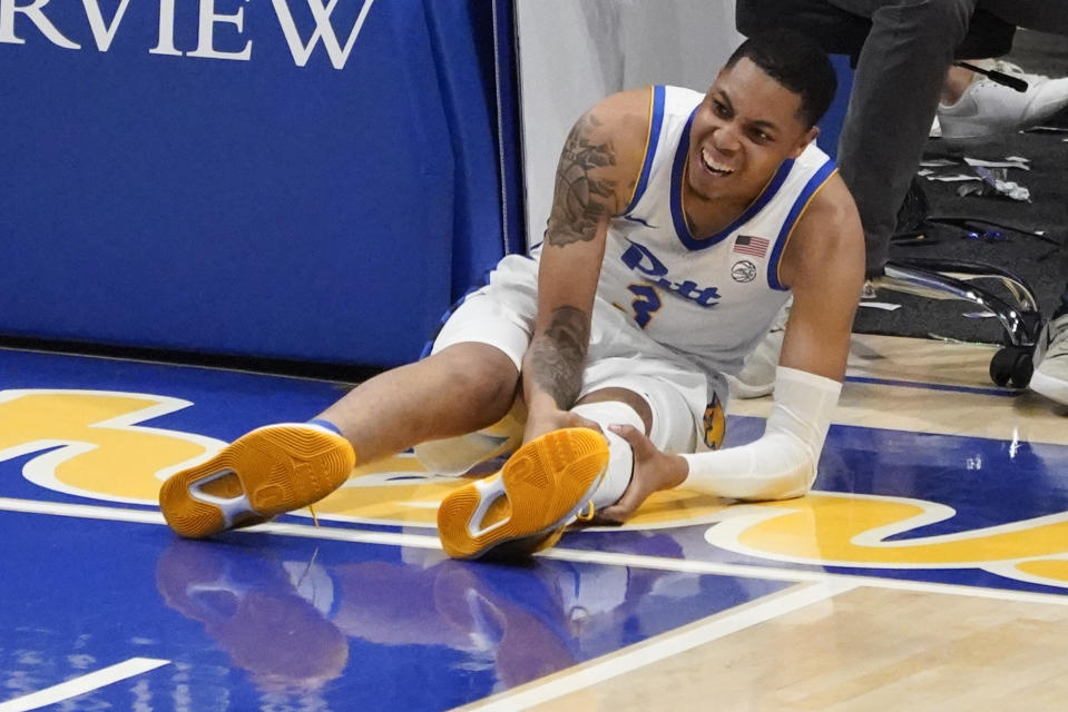 Pittsburgh's Greg Elliott (3) grabs his leg after being injured during the second half of an NCAA college basketball game against West Virginia, Friday, Nov. 11, 2022, in Pittsburgh. Elliott left the game for awhile but returned to play. (AP Photo/Keith Srakocic)