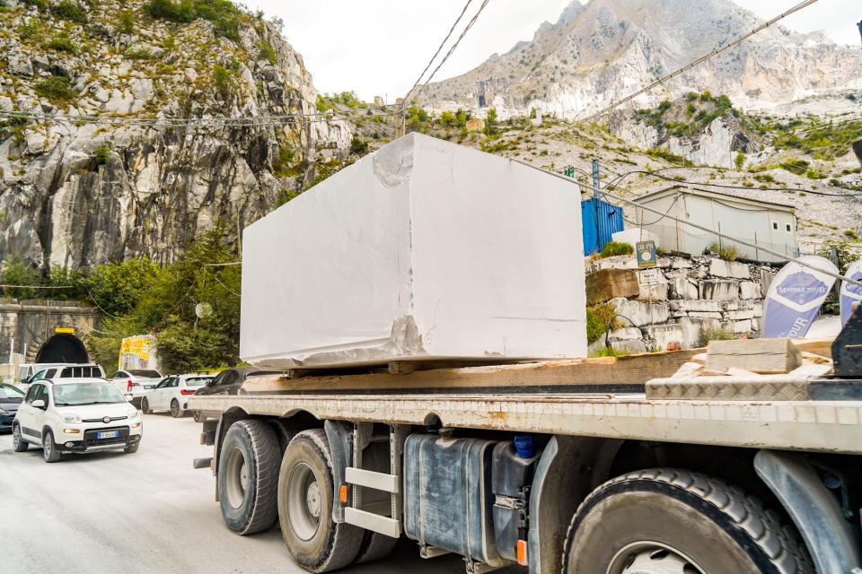 A truck drives with a gigantic slab of marble on the bed