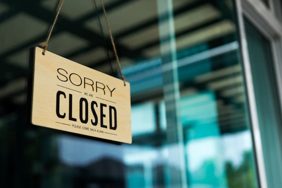 A "we're closed" sign hung on a store front