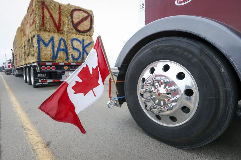 The Canadian flag is reflected in a wheel hub as anti-COVID-19 vaccine mandate demonstrators gather as a truck convoy blocks the highway at the busy U.S. border crossing in Coutts, Alberta, Canada, Monday, Jan. 31, 2022. Thousands of antivaccine protesters descended on Canada's capital of Ottawa in frigid temperatures to protest vaccine mandates, masks and restrictions over the weekend and some remain, blocking traffic around Parliament Hill in what has been the biggest pandemic protest in the country to date. (Jeff McIntosh/The Canadian Press via AP)