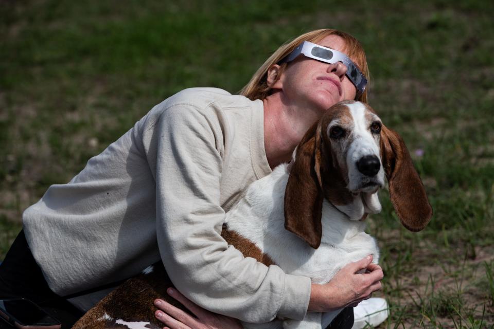 Karie Heathcoat of Houston holds basset hound Fancy and watches the annular solar eclipse at Lake Corpus Christi State Park on Saturday, Oct. 14, 2023, in Mathis, Texas.