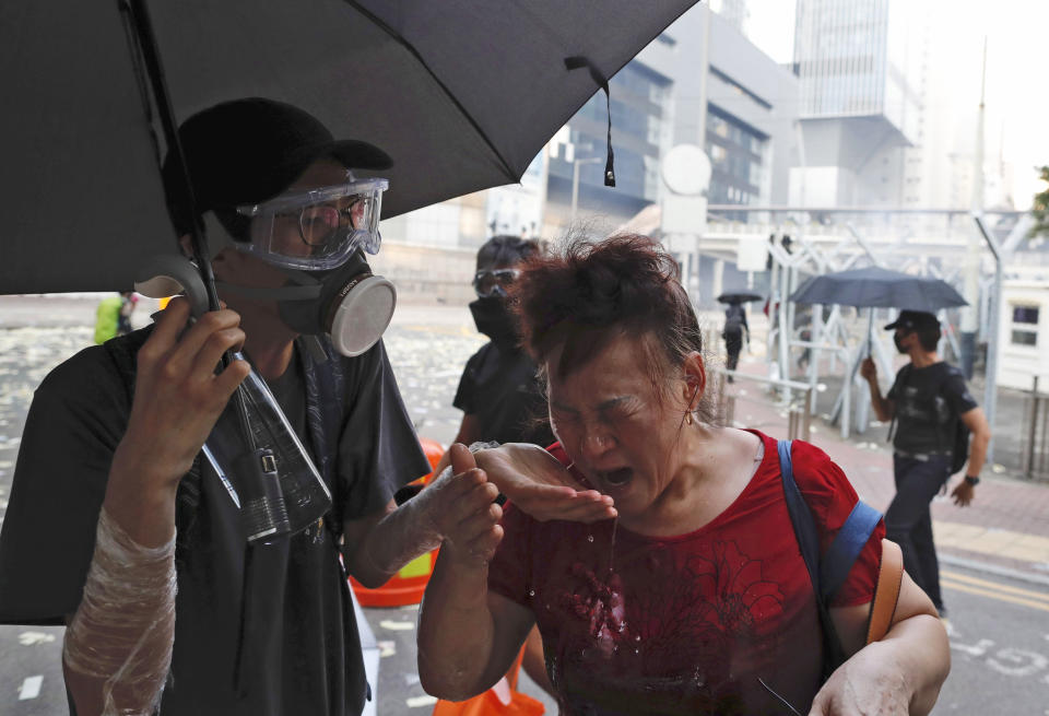 A black-clad protestor splashes water on the face of a woman after police fired tear gas shells in Hong Kong, Oct. 1, 2019. (Photo: Gemunu Amarasinghe/AP)