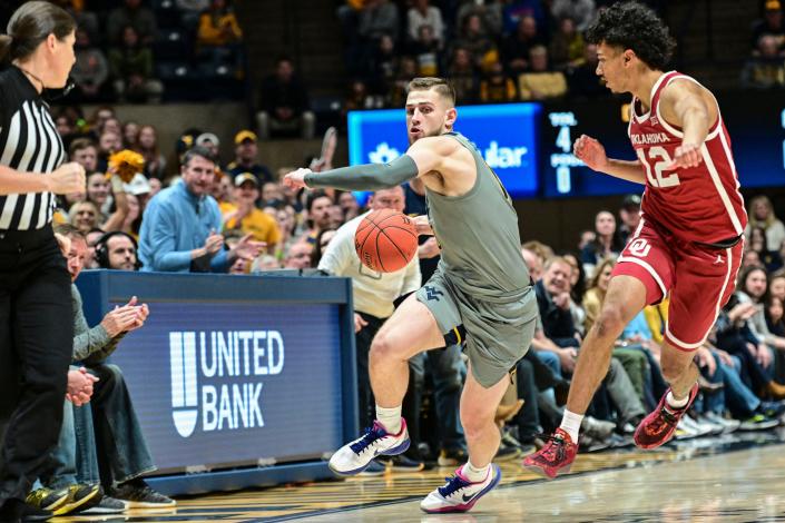 West Virginia guard Erik Stevenson (10) protects the ball from Oklahoma guard Milos Uzan (12) during the first half of an NCAA college basketball game in Morgantown, W.Va., Saturday, Feb. 4, 2023. (AP Photo/William Wotring)