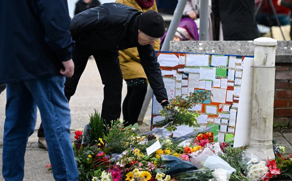 People lay flowers at the vigil for the deceased asylum seeker, outside Portland Port