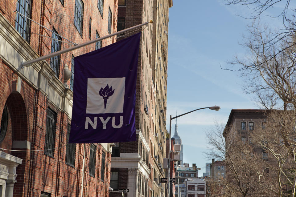 New York, MY, USA - March 22, 2016: New York University buildings on Macdougal Street at 37 Washington Square West. A purple flag with the NYU logo hangs above an entrance to one of the college buildings. In the distance, the Empire State Building appears above buildings on West 8th Street. (Photo: CribbVisuals via Getty Images)